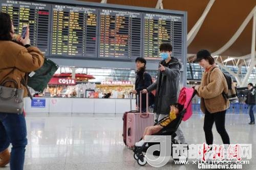 旅客帶著孩子前往辦票柜臺辦理登機手續(xù)?！∫罅⑶?攝