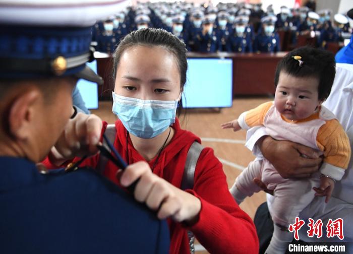 新消防員楊振的妻子彭莉與女兒現(xiàn)場見證丈夫加入“火焰藍”的神圣時刻?！⒅铱?攝
